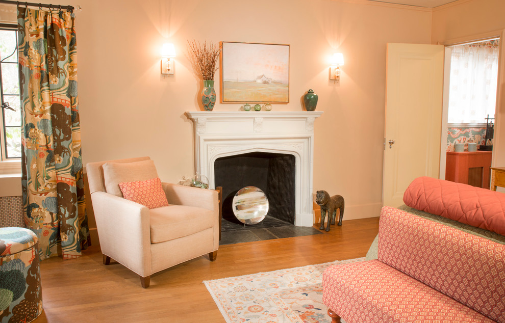 Cette photo montre une grande chambre d'amis éclectique avec un mur beige, un sol en bois brun, une cheminée standard et un manteau de cheminée en plâtre.