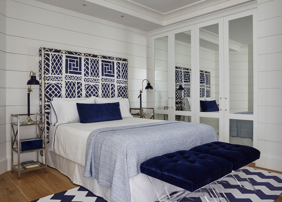 Coastal guest bedroom in Miami with white walls and light hardwood flooring.