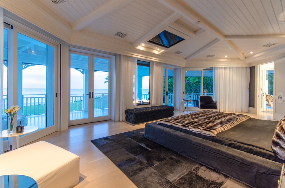 Diseño de dormitorio principal costero extra grande con suelo de madera clara, paredes blancas, suelo beige y machihembrado