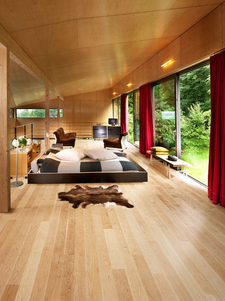 This is an example of a medium sized contemporary master bedroom in Chicago with brown walls and light hardwood flooring.