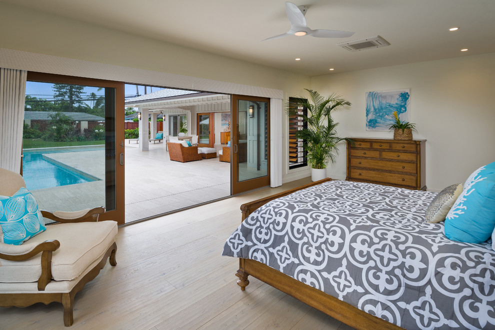 Large beach style master bedroom in Hawaii with white walls, light hardwood flooring and beige floors.