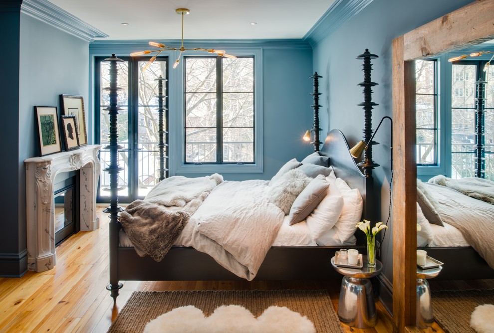 Idée de décoration pour une chambre bohème avec un mur bleu, un sol en bois brun, une cheminée standard et un manteau de cheminée en pierre.