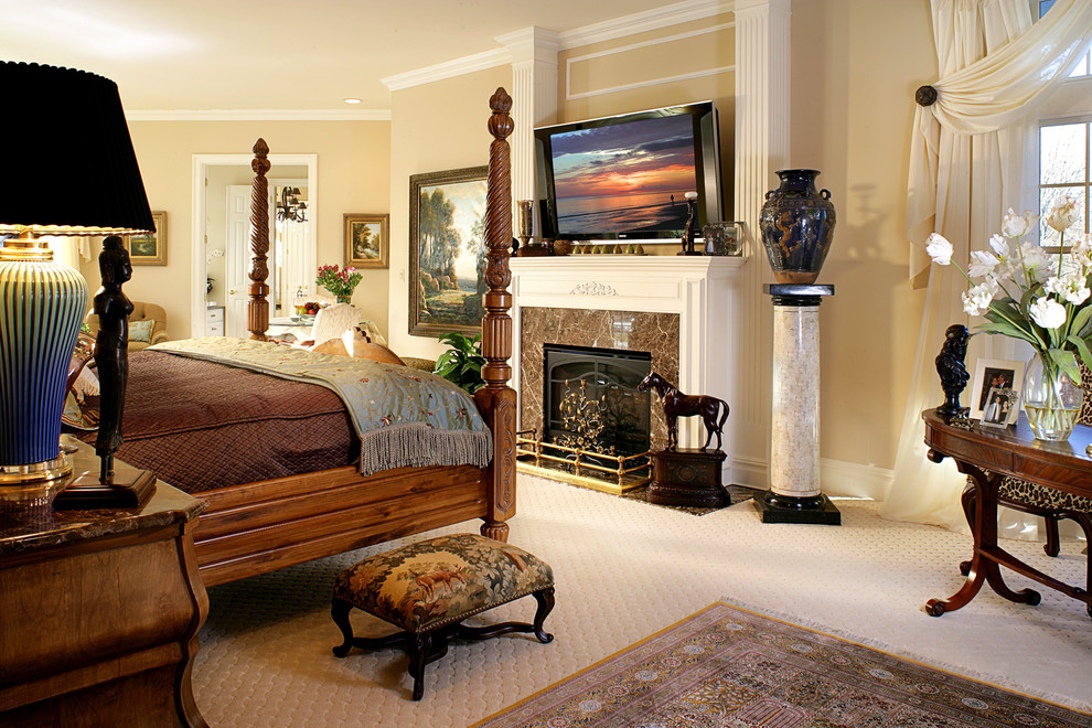 На фото: большая хозяйская спальня в классическом стиле с бежевыми стенами, ковровым покрытием, стандартным камином, фасадом камина из камня, бежевым полом и телевизором с