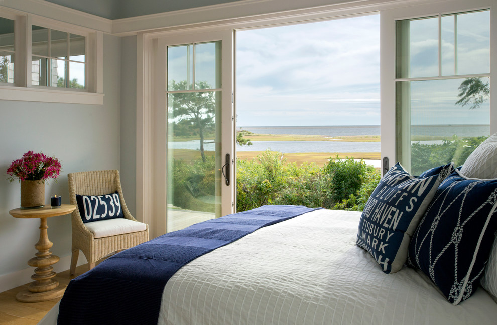 This is an example of a beach style bedroom in Boston with blue walls and medium hardwood flooring.