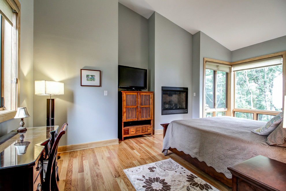 Foto de dormitorio principal rural de tamaño medio con paredes grises, suelo de madera clara, todas las chimeneas y marco de chimenea de metal