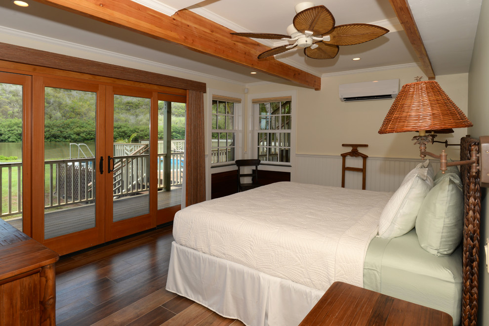 Immagine di una camera degli ospiti tropicale di medie dimensioni con pareti beige, pavimento in legno massello medio, nessun camino e pavimento marrone