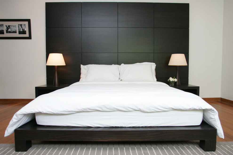 This is an example of a contemporary bedroom in Other with white walls and medium hardwood flooring.