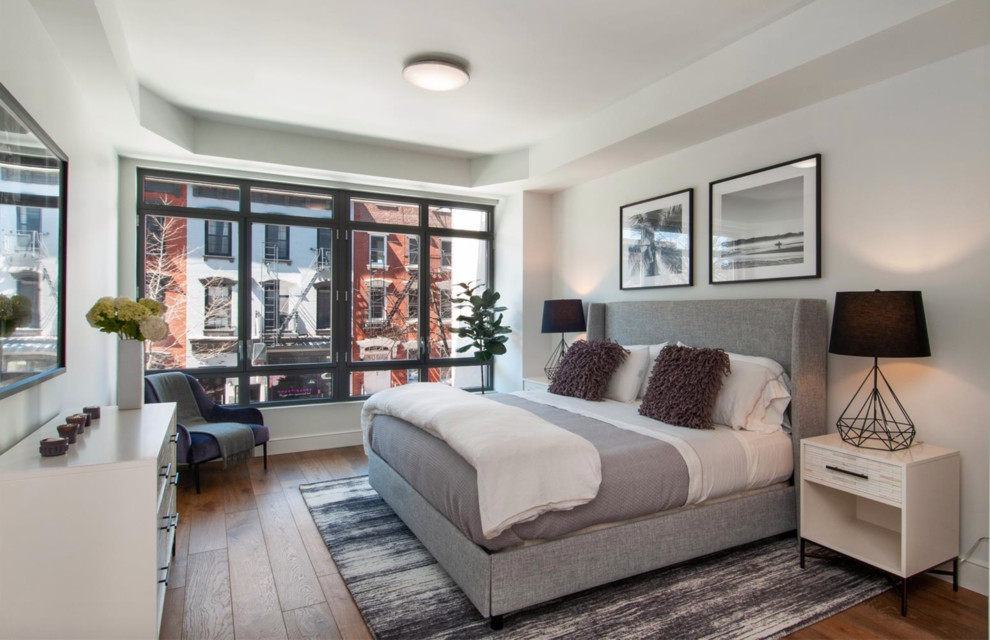 Klassisches Hauptschlafzimmer ohne Kamin mit weißer Wandfarbe, braunem Holzboden und braunem Boden in New York