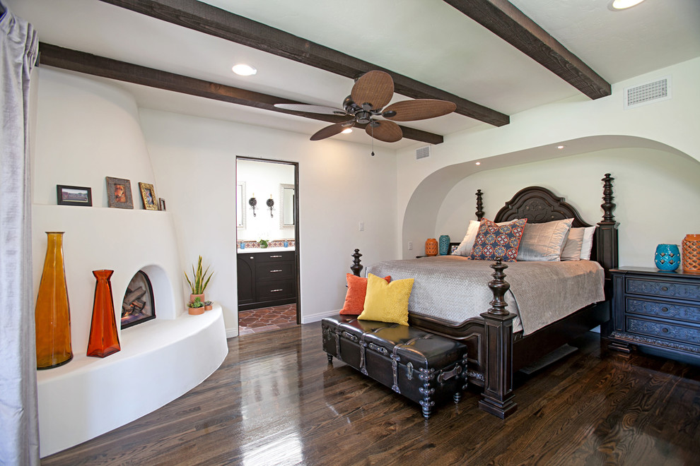 Imagen de dormitorio principal tradicional de tamaño medio con suelo de madera oscura, chimenea de esquina y marco de chimenea de yeso