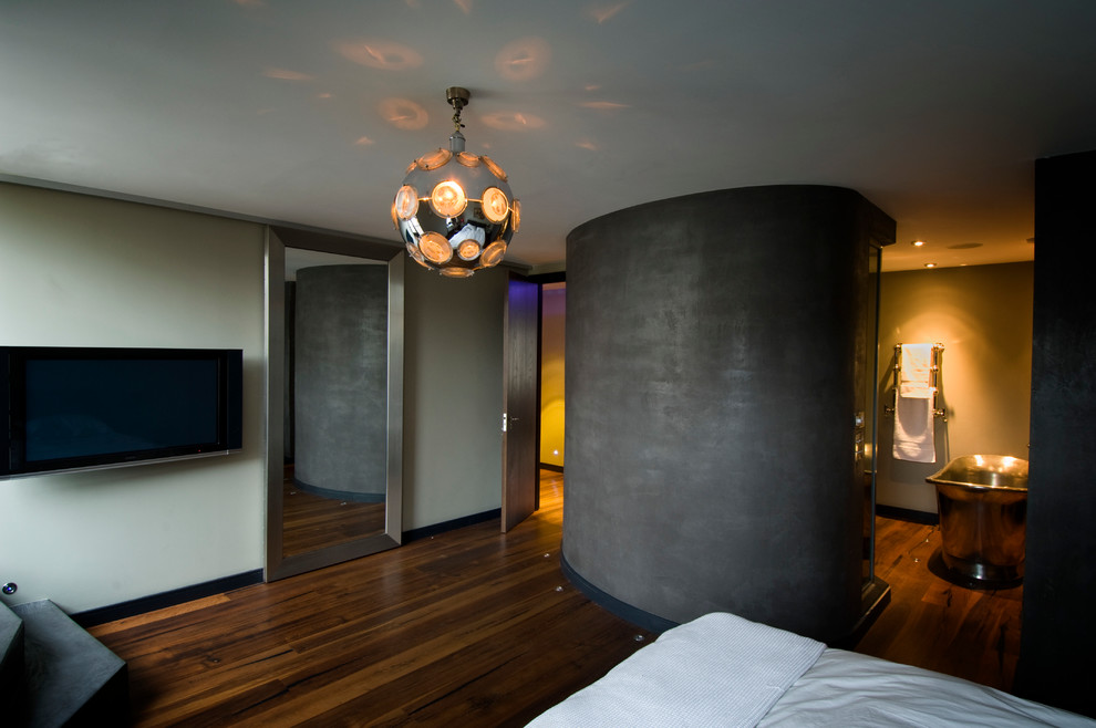Modelo de dormitorio tipo loft actual grande con paredes grises y suelo de madera oscura