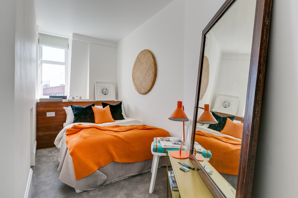 Immagine di una piccola camera da letto design con pareti bianche, moquette e pavimento grigio