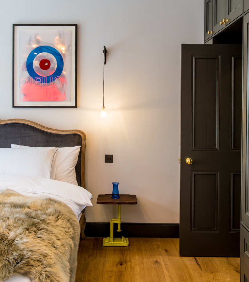 ロンドンにあるトラディショナルスタイルのおしゃれな客用寝室 (淡色無垢フローリング、石材の暖炉まわり) のインテリア
