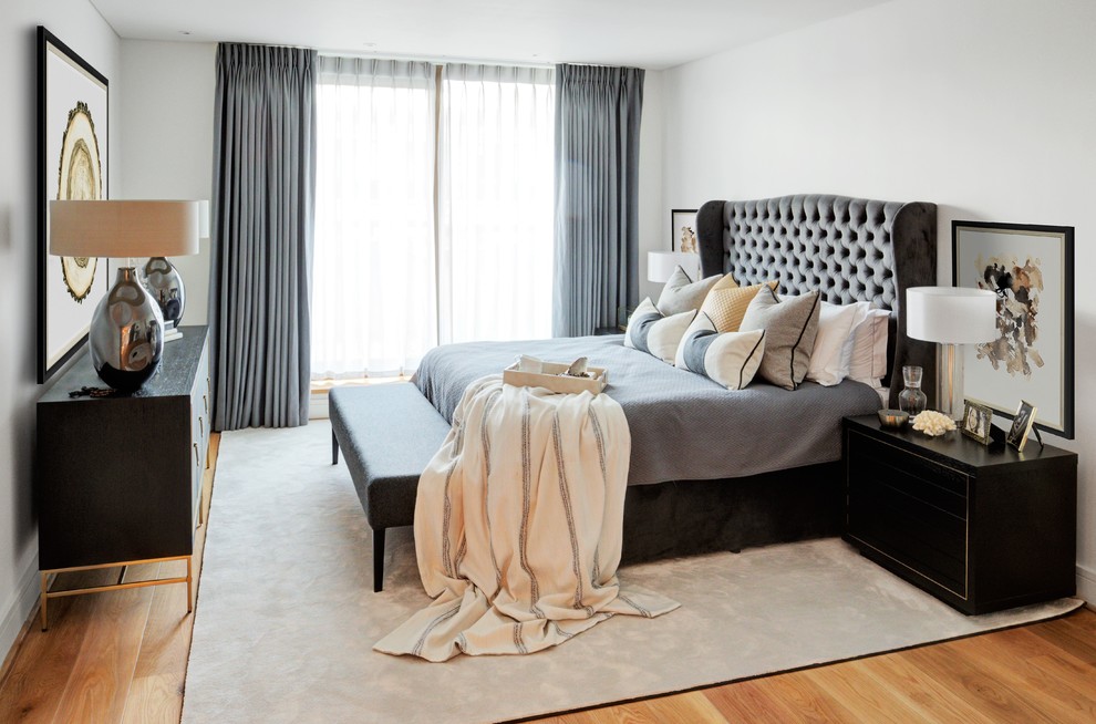 Example of a mid-sized transitional master light wood floor and brown floor bedroom design in London with white walls and no fireplace