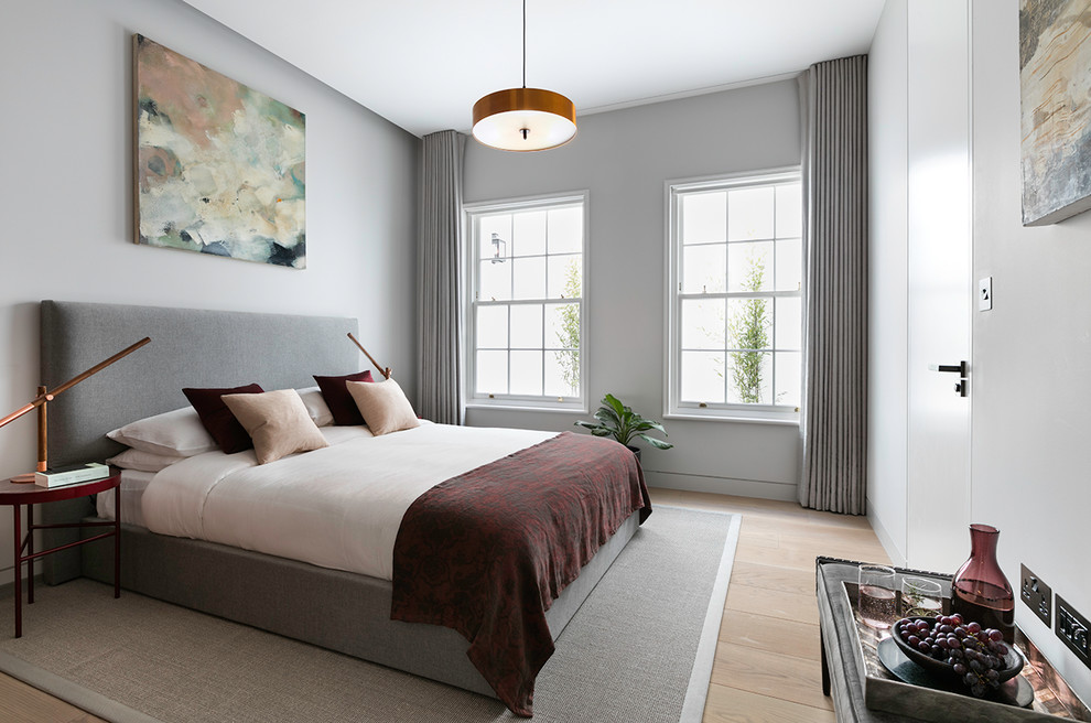 This is an example of a large contemporary guest and grey and brown bedroom in London with grey walls, light hardwood flooring and brown floors.