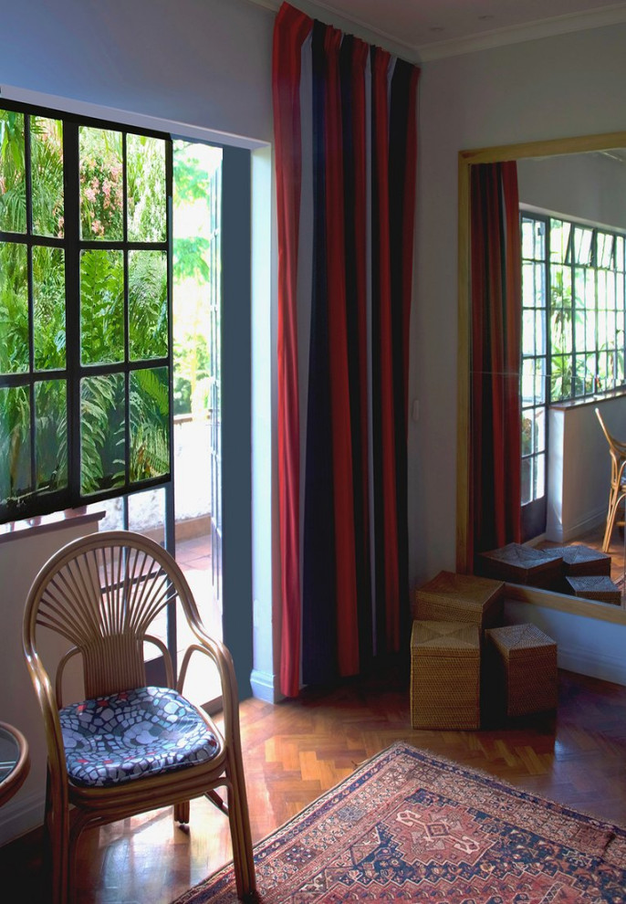 Imagen de habitación de invitados tropical grande con paredes blancas, suelo de madera oscura y suelo marrón