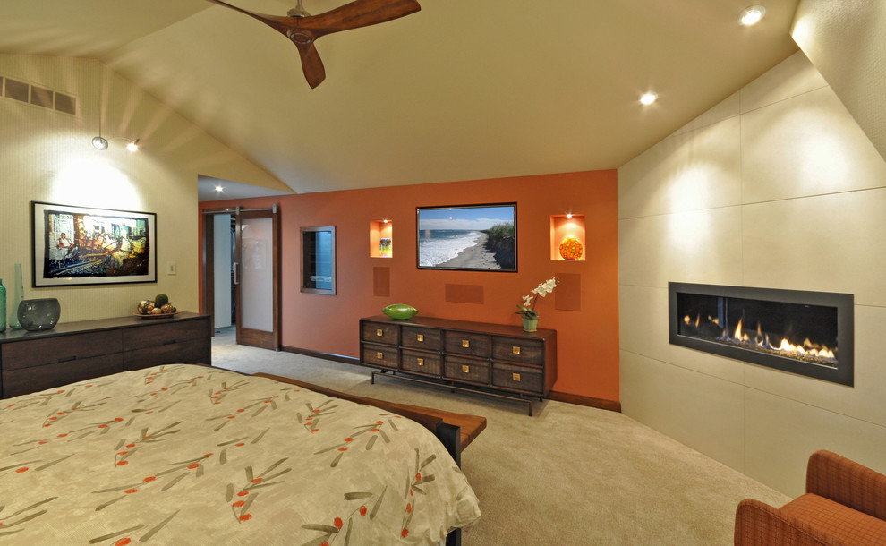 Foto di una camera matrimoniale minimal di medie dimensioni con pareti arancioni, moquette, camino lineare Ribbon e cornice del camino piastrellata