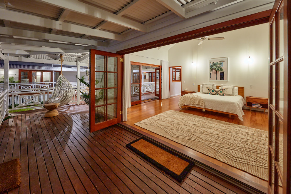 Ejemplo de dormitorio tropical con paredes blancas, suelo de madera oscura y suelo marrón