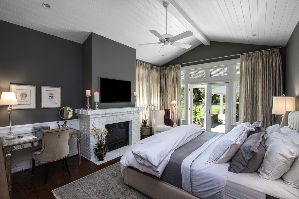На фото: хозяйская спальня среднего размера в стиле неоклассика (современная классика) с серыми стенами, темным паркетным полом, стандартным камином, фасадом камина из кирпича и телевизором
