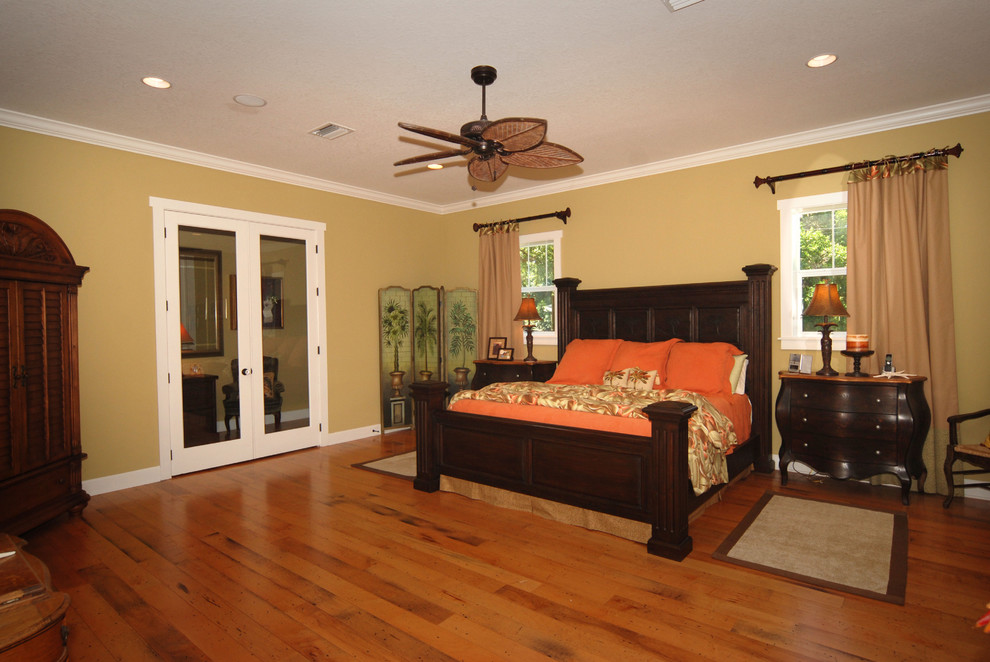 Example of a mid-sized island style master medium tone wood floor bedroom design in Tampa with beige walls and no fireplace