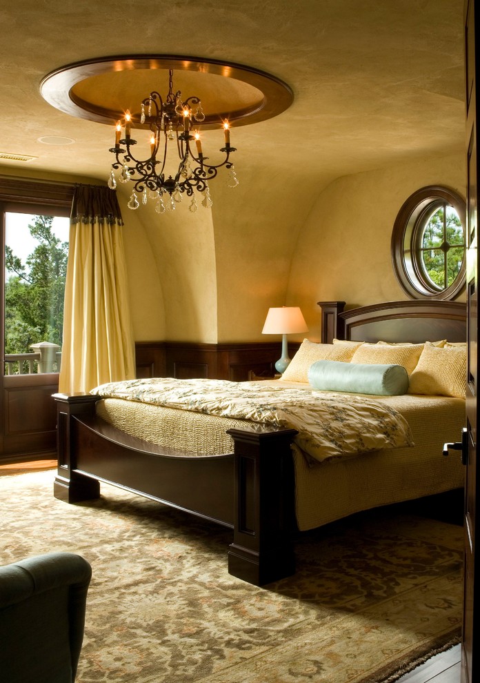 This is an example of a traditional master bedroom in Charleston with yellow walls and dark hardwood flooring.