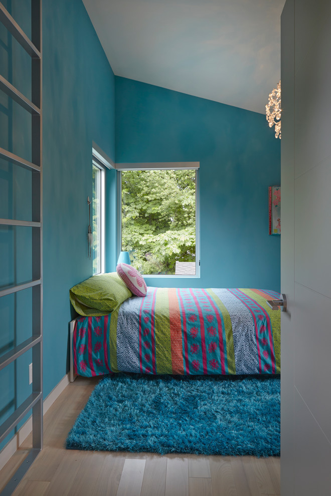 Ejemplo de dormitorio tipo loft moderno de tamaño medio con paredes azules y suelo de madera clara