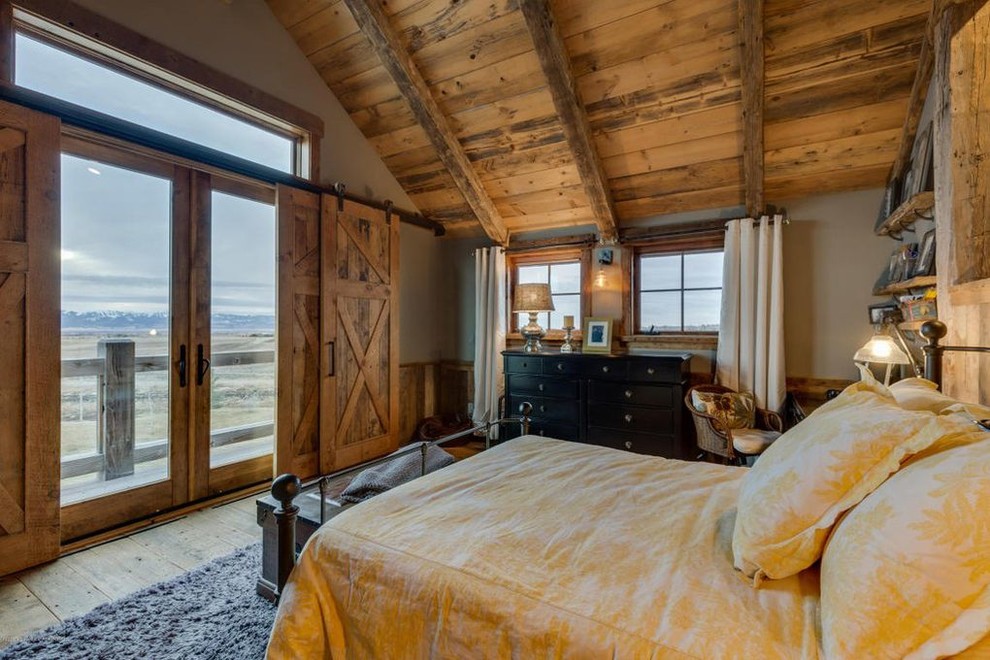 Large rustic guest and grey and brown bedroom in Other with medium hardwood flooring, grey walls, no fireplace, brown floors, exposed beams and panelled walls.