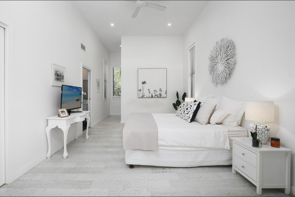 Diseño de dormitorio principal costero de tamaño medio con suelo laminado y suelo blanco