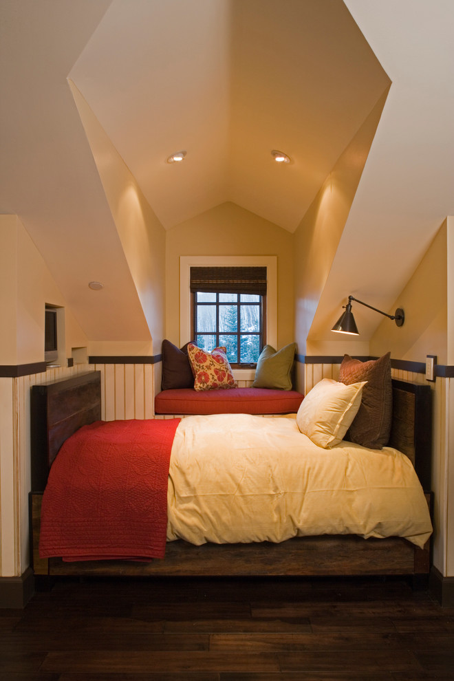Modelo de habitación de invitados tradicional con paredes beige, suelo de madera oscura y techo inclinado