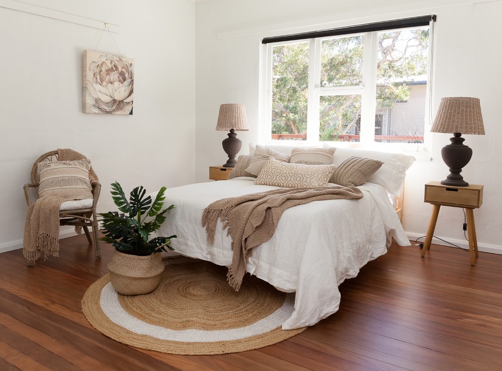 Immagine di una camera degli ospiti stile marino con pareti bianche, nessun camino, pavimento marrone e pavimento in legno massello medio