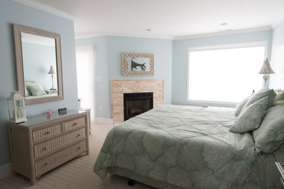 This is an example of a medium sized beach style master bedroom in Other with blue walls, carpet, a standard fireplace, a stone fireplace surround and beige floors.