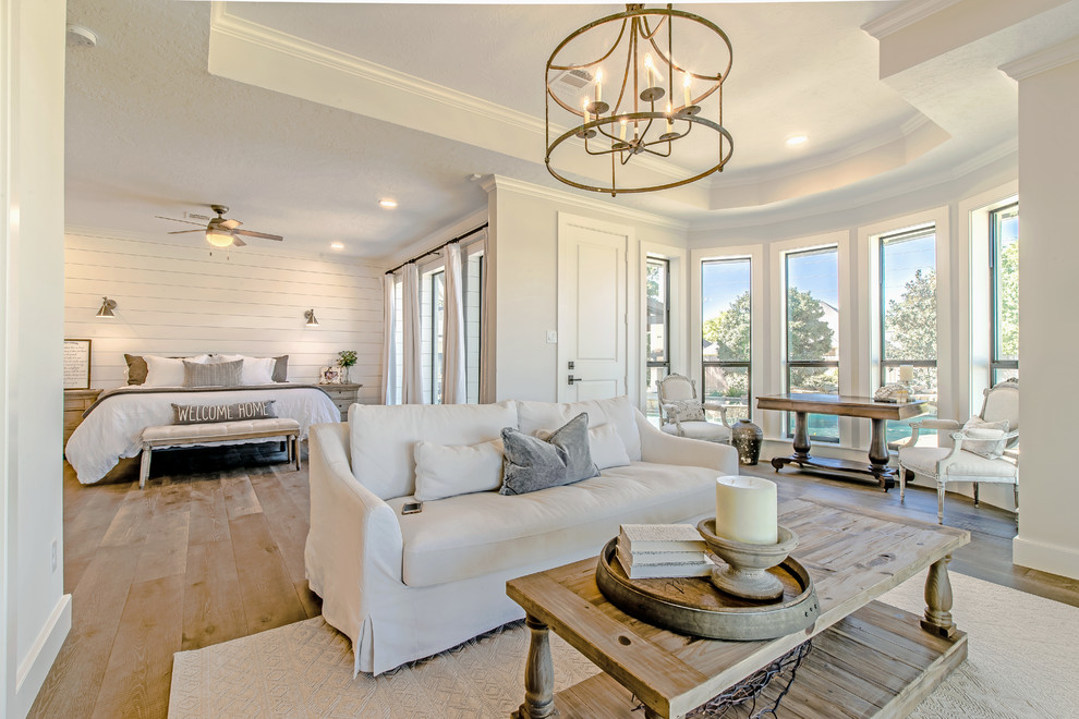 This is an example of a rural master bedroom in Houston with white walls, light hardwood flooring and beige floors.