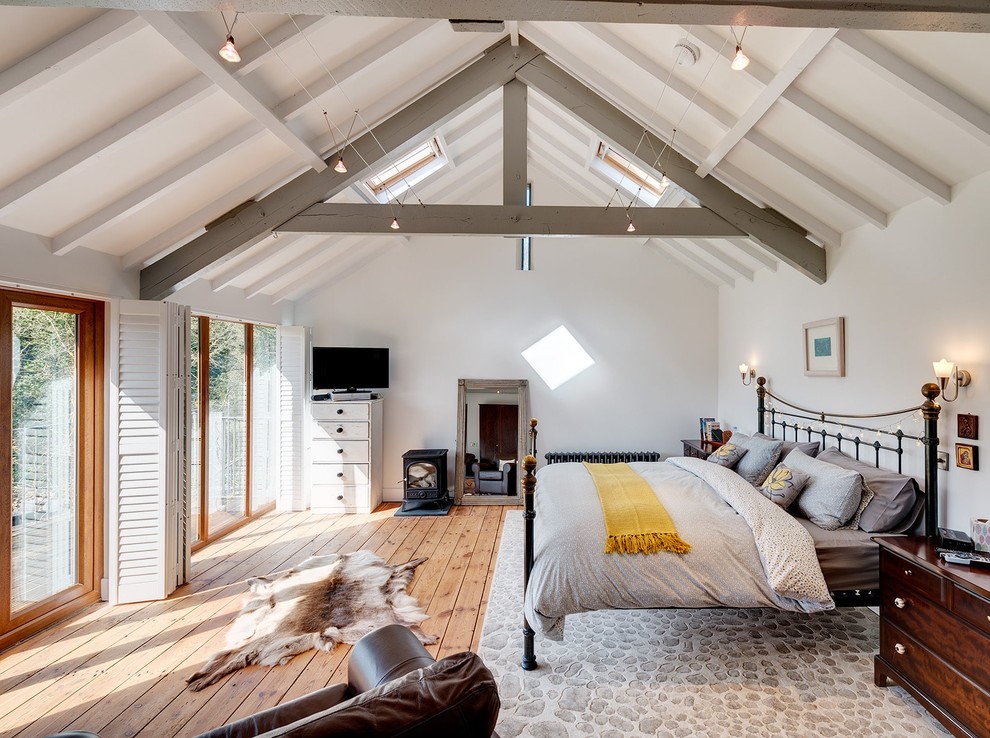 Landhaus Schlafzimmer mit weißer Wandfarbe, braunem Holzboden und braunem Boden in Sonstige