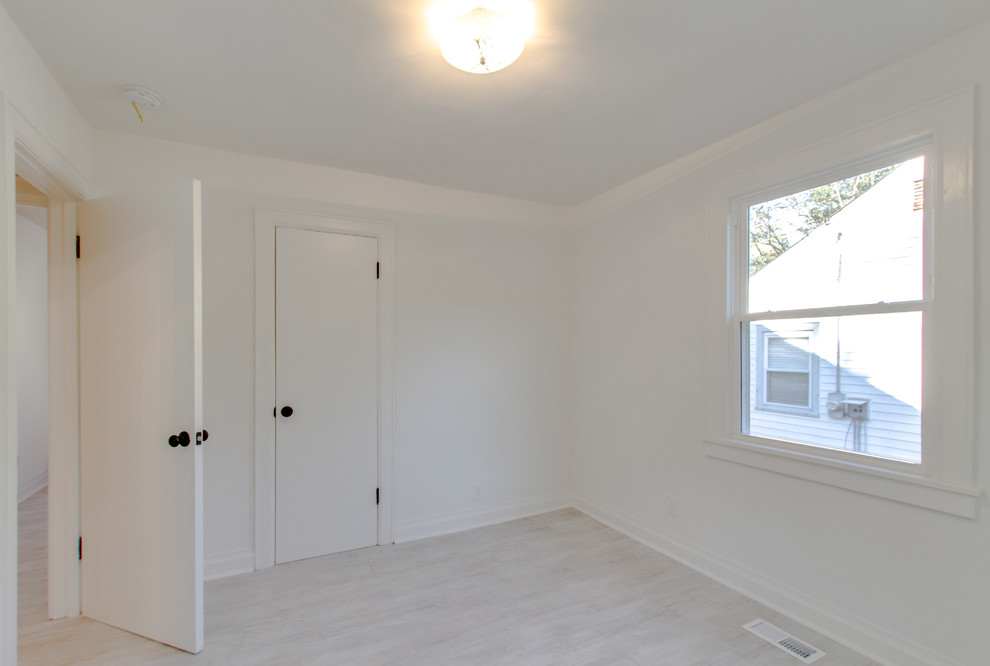 Imagen de habitación de invitados moderna de tamaño medio con paredes blancas, suelo de madera clara y suelo blanco