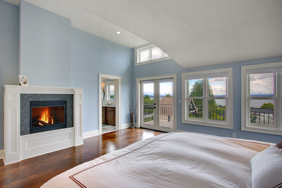 Exemple d'une chambre chic avec un mur bleu, un sol en bois brun et une cheminée standard.