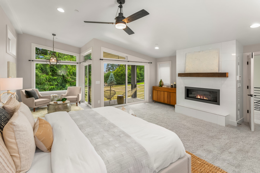 Design ideas for an expansive contemporary master bedroom in Seattle with carpet, grey floors, beige walls, a ribbon fireplace, a tiled fireplace surround and a chimney breast.