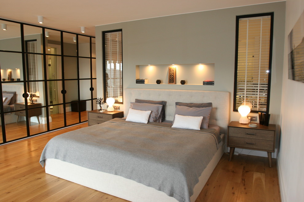 Modelo de dormitorio actual con paredes grises y suelo de madera en tonos medios