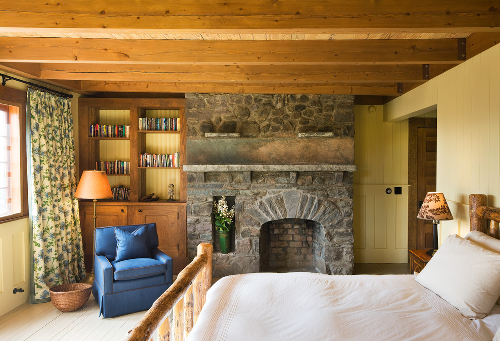 Mountain style guest light wood floor bedroom photo in New York with yellow walls, a standard fireplace and a stone fireplace