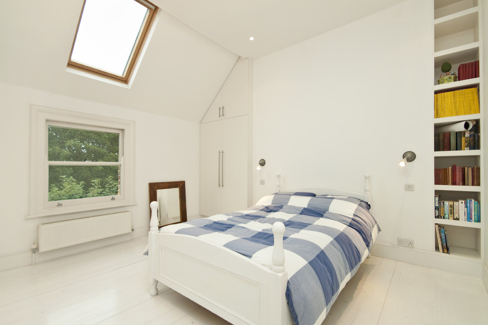 На фото: спальня в скандинавском стиле с белыми стенами и деревянным полом без камина с