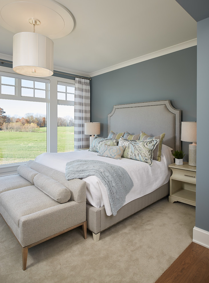 This is an example of a country master bedroom in Grand Rapids with blue walls, carpet, beige floors and feature lighting.