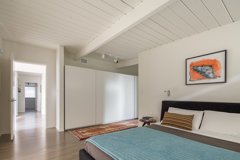 This is an example of a retro master bedroom in Denver with white walls and medium hardwood flooring.