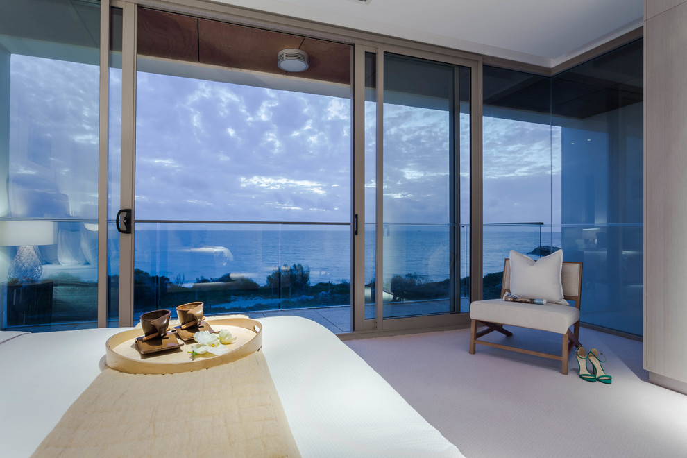 Imagen de dormitorio principal tropical de tamaño medio sin chimenea con paredes blancas y moqueta