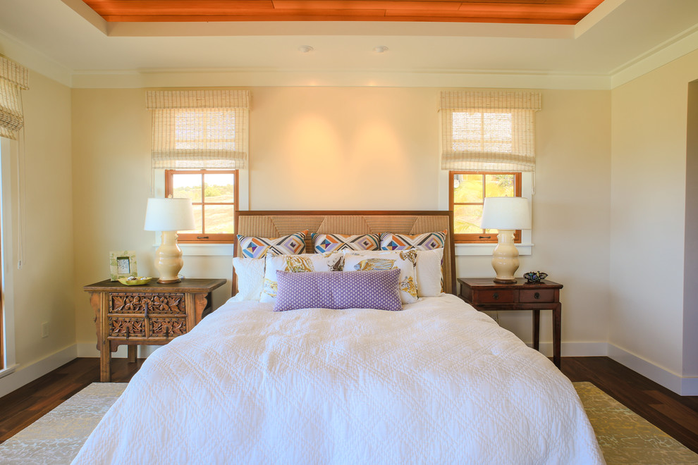 Modelo de dormitorio exótico con paredes beige y suelo de madera oscura
