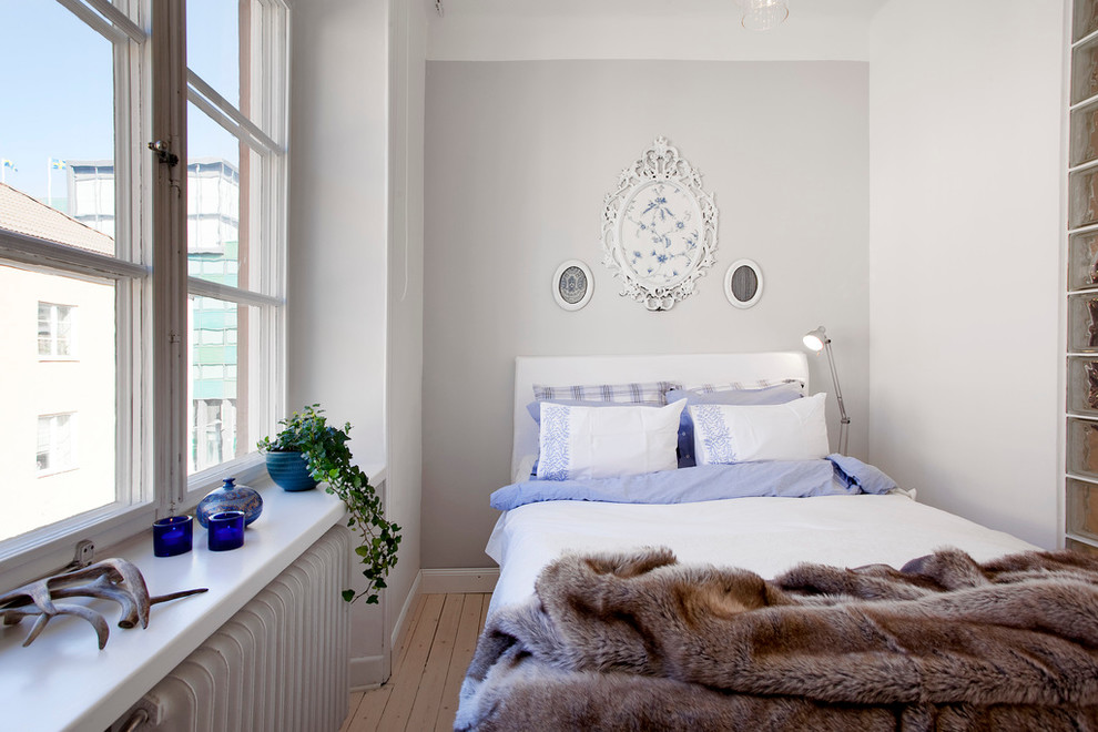 Foto på ett litet minimalistiskt gästrum, med grå väggar och ljust trägolv