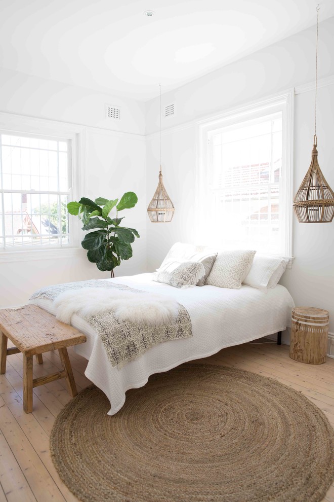 Ejemplo de dormitorio principal rústico de tamaño medio con paredes blancas, suelo de madera clara y chimenea de esquina