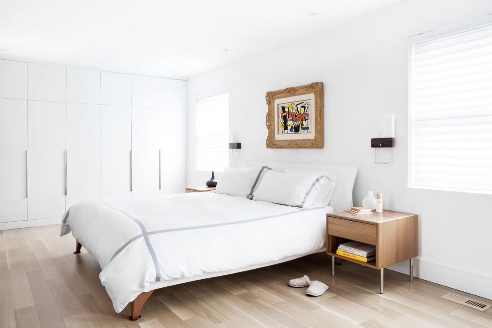Design ideas for a large modern master bedroom in Montreal with white walls, light hardwood flooring, no fireplace and beige floors.