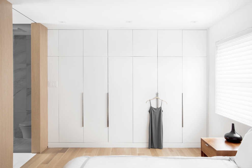 Large modern master bedroom in Montreal with white walls and light hardwood flooring.