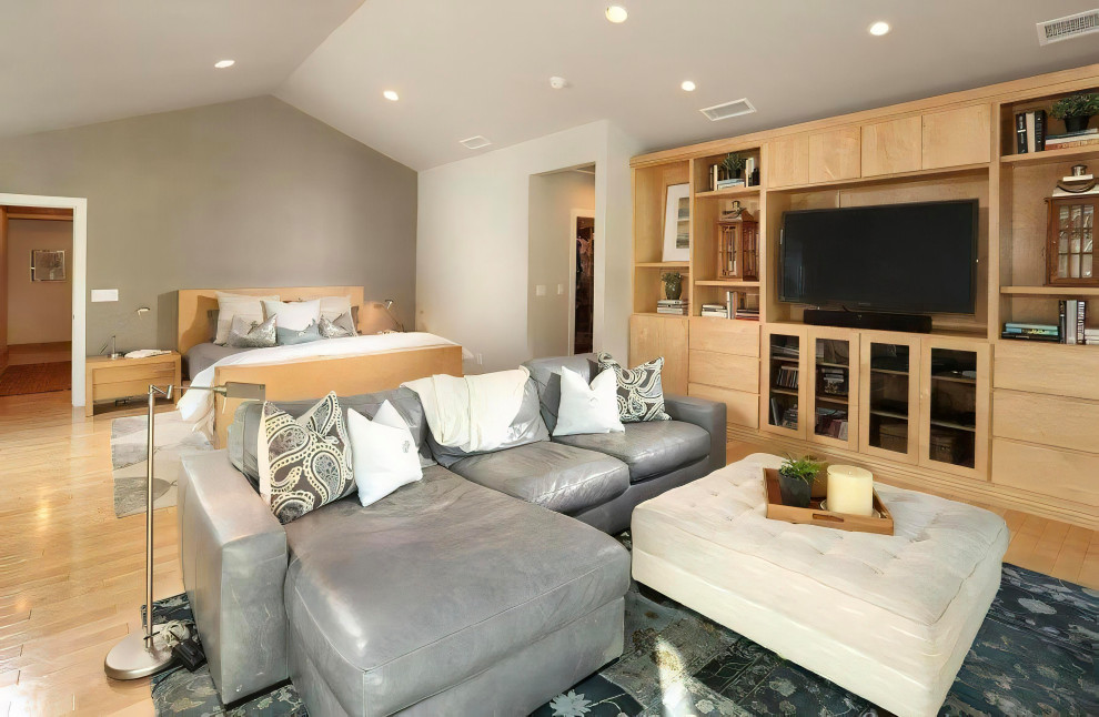 ロサンゼルスにある広いトランジショナルスタイルのおしゃれな主寝室 (グレーの壁、淡色無垢フローリング、横長型暖炉、積石の暖炉まわり、ベージュの床、三角天井、壁紙)