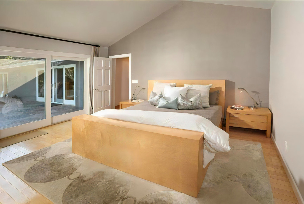ロサンゼルスにある広いトランジショナルスタイルのおしゃれな主寝室 (グレーの壁、淡色無垢フローリング、横長型暖炉、積石の暖炉まわり、ベージュの床、三角天井、壁紙) のインテリア
