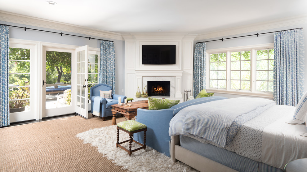 На фото: большая хозяйская спальня в классическом стиле с белыми стенами, ковровым покрытием и угловым камином с