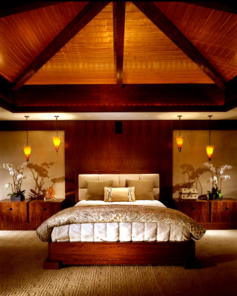 Example of a large island style master carpeted bedroom design in San Diego with beige walls, a standard fireplace and a stone fireplace